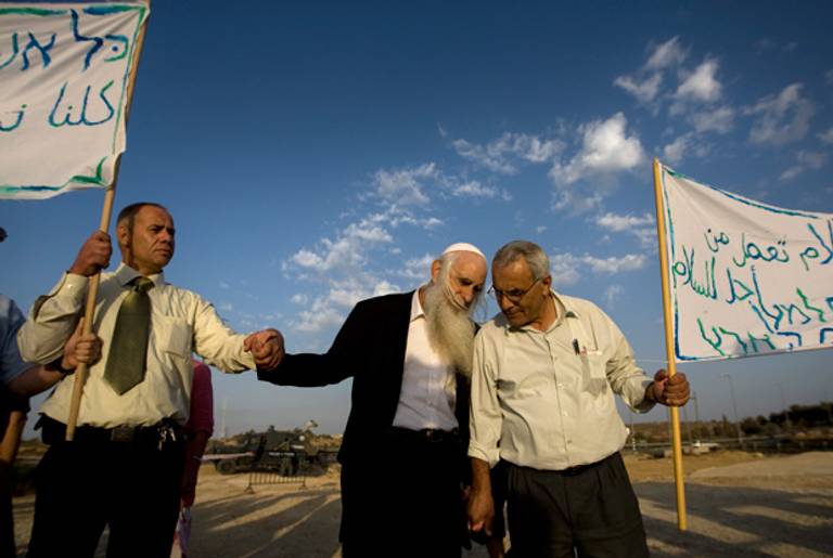 Israeli settler leader and peace activist Rabbi Menachem Froman, center, marches with Palestinians in protest the burning of a West Bank mosque apparently by extremist settlers, near the West Bank village of Beit Fajjar, near Bethlehem, Tuesday, Oct. 5, 2010.(Sebastian Scheiner/AP)