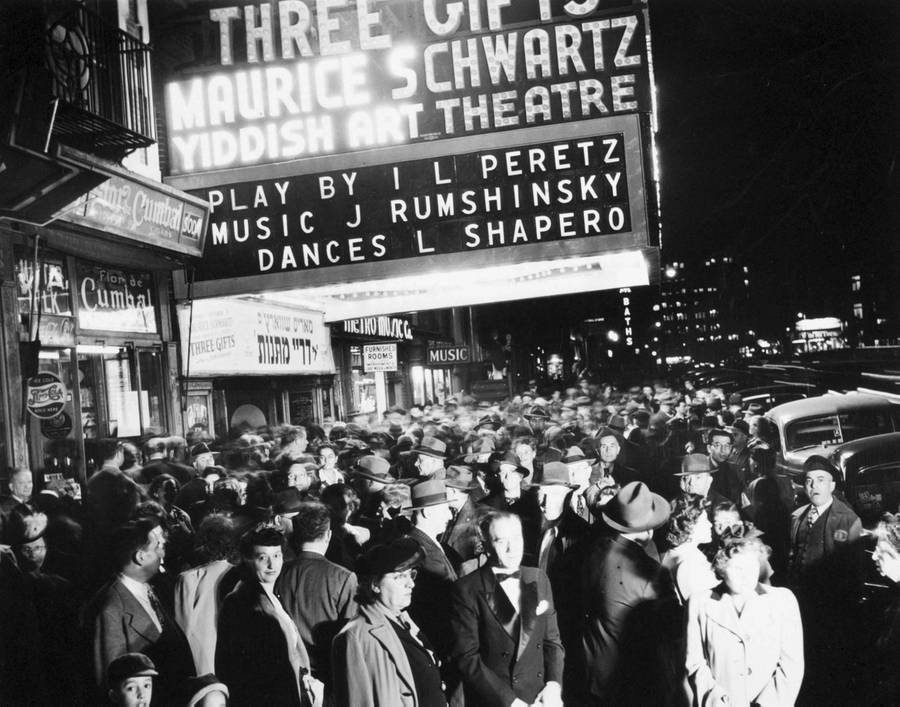 A crowd of people on the sidewalk in front of the Yiddish Art Theatre at Second Avenue and Fourth Street, New York, 1945. The theater marquee announces performances of Maurice Schwartz’s musical ‘Three Gifts,’ music by Joseph Rumshinsky.
