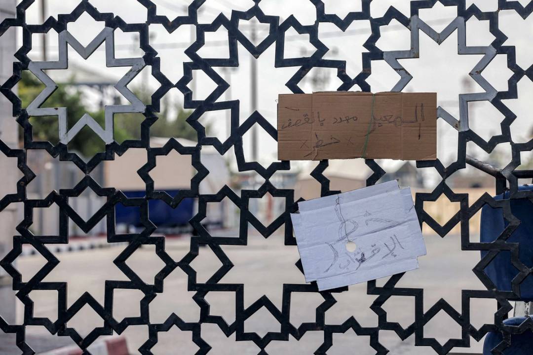 Cardboard signs with text in Arabic reading 'the crossing is under threat of bombardment, danger to approach' on the fence of the Rafah border crossing with Egypt in the south of the Gaza Strip, on Oct. 19, 2023