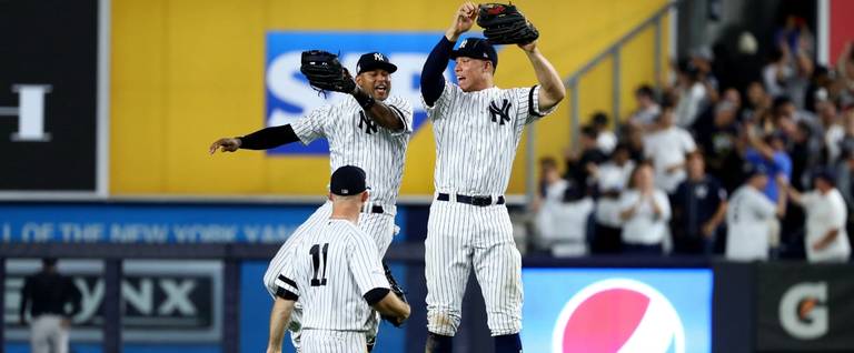 Aaron Judge #99 of the New York Yankees celebrates with teammates Aaron Hicks #31 and Brett Gardner #11 after defeating the Cleveland Indians in Game Four of the American League Divisional Series at Yankee Stadium on October 9, 2017 in the Bronx borough of New York City.