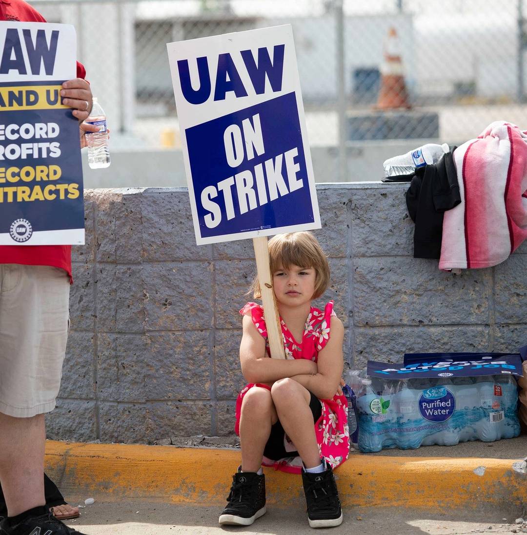A young supporter holds a sign as United Auto Workers members strike at the Ford Michigan Assembly Plant in Wayne, Michigan, on Sept. 16, 2023. This is the first time in history that the UAW is striking all of the Big Three automakers—Ford, General Motors, and Stellantis—at the same time.