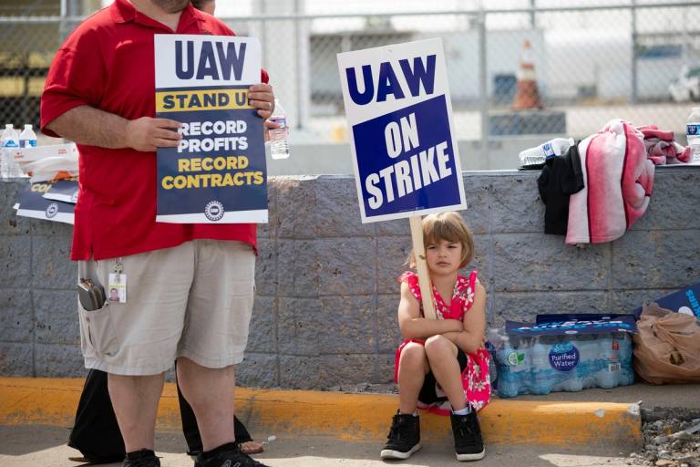 A young supporter holds a sign as United Auto Workers members strike at the Ford Michigan Assembly Plant in Wayne, Michigan, on Sept. 16, 2023. This is the first time in history that the UAW is striking all of the Big Three automakers—Ford, General Motors, and Stellantis—at the same time.
