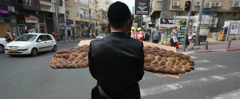 An ultra-Orthodox Jewish man carries a challah on a street during Purim in Bnei Brak, Israel on March 24, 2016. 