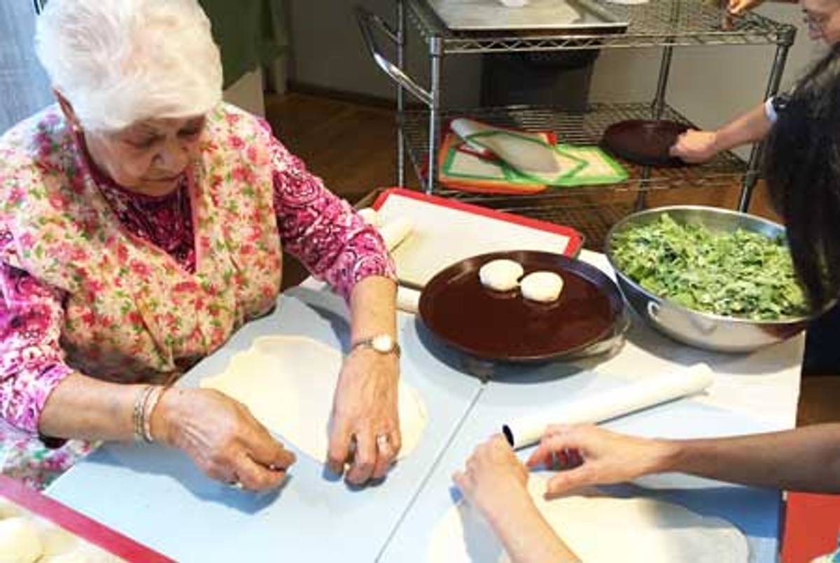 Julie DeLeon, a member of Congregation Ezra Bessaroth, rolls out the oily dough used to make bulemas, or boyos, spinach and cheese filled pastries. (Photo courtesy Congregation Ezra Bessaroth)