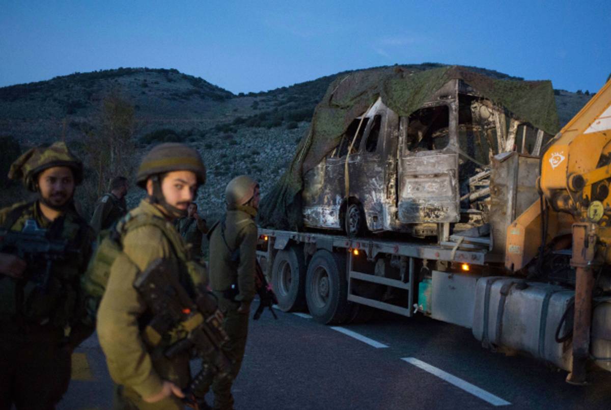 Israeli soldiers look at a burned-out vehicle after a Hezbollah attack on the Israel-Lebanon border on January 28, 2015(Menahem Kahana/AFP/Getty Images)