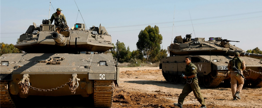 Israeli soldiers gather around Merkava tanks stationed along the Israeli border with the Gaza Strip on Nov. 13, 2018. 