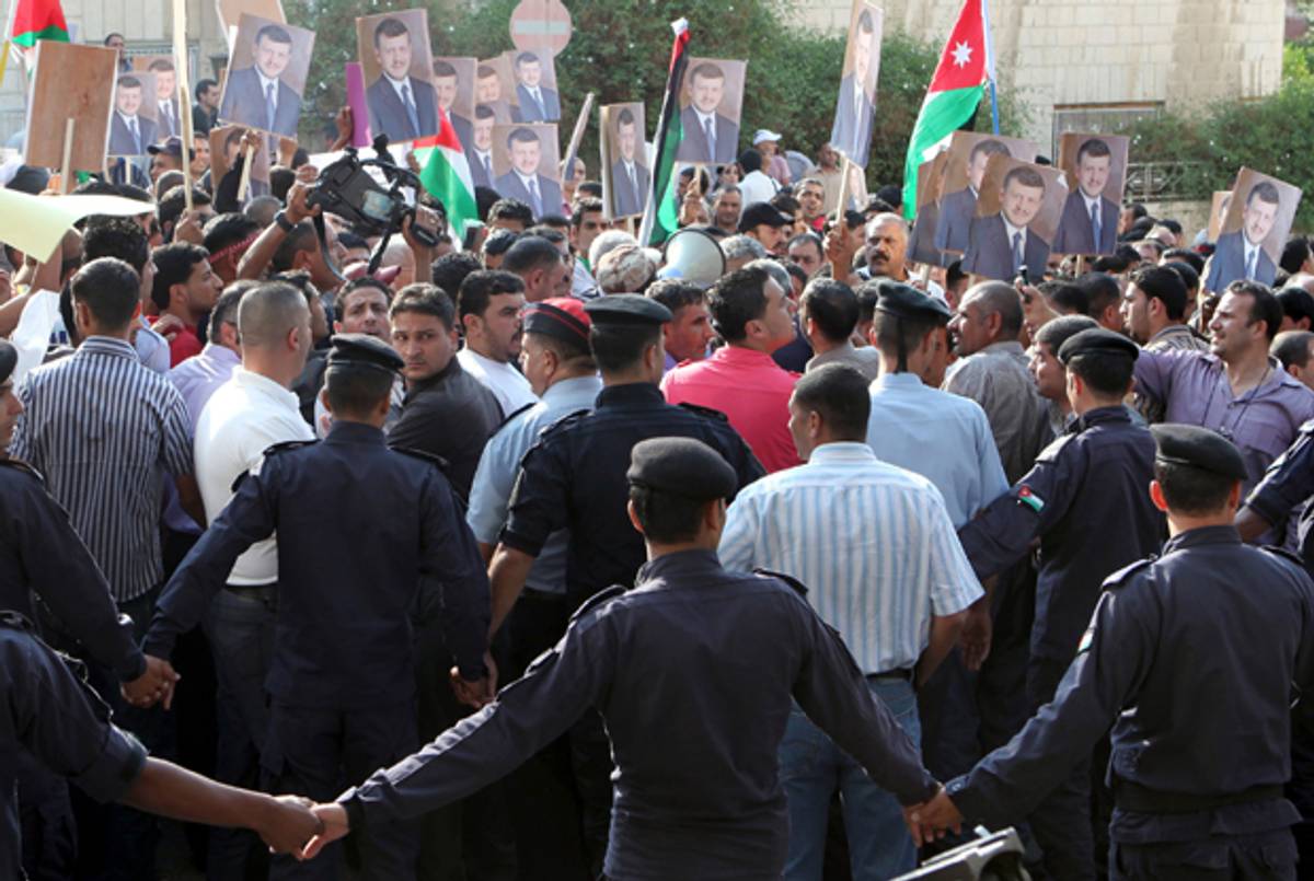 Jordanian police control a crowd from the city of Tafileh as they protest outside the offices of the Agence France Presse on June 14, 2011, after the AFP reported that King Abdullah's motorcade was attacked with stones during a visit to the city.(Khalil Mazraawi/AFP/Getty Image)