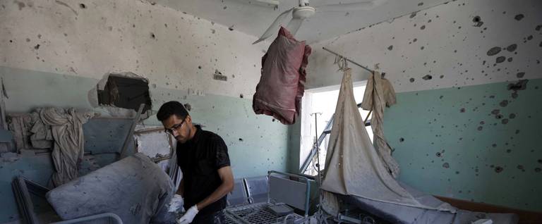 A Palestinian employee inspects damages at the Al-Aqsa Martyrs hospital in Deir al-Balah, in the central Gaza Strip, after the building was shelled by the Israeli army on July 21, 2014, killing five people and wounding at least 70