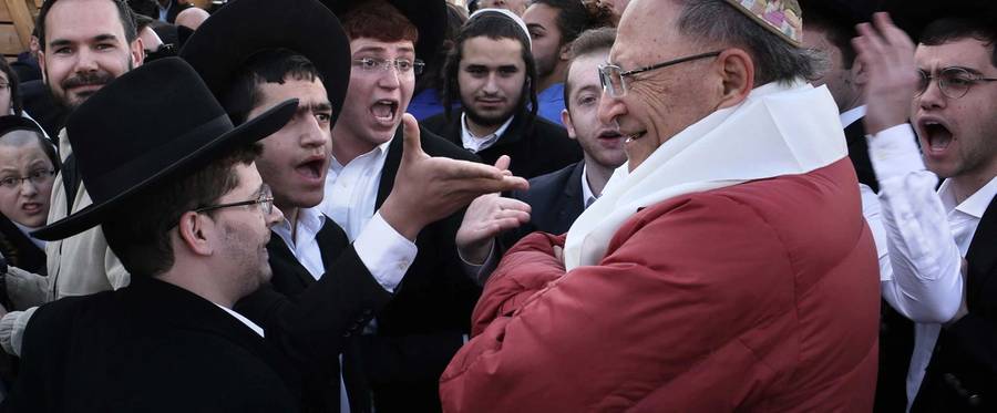 Ultra-Orthodox Jewish men yell at a member  of the liberal Jewish religious group Women of the Wall, during a demonstration against the liberal group, on February 27, 2017.