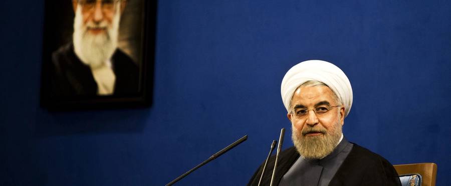 Iranian President Hassan Rouhani listens, sitting next to a portrait of supreme leader Ayatollah Ali Khamenei, during a press conference in Tehran on June 13, 2015.