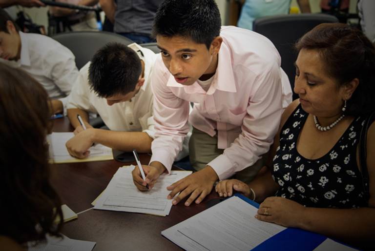 Bolivian Diego Mariaca(C), his mother Ingrid Vaca(R), and brother Gustavo Mariaca(L) fill out paperwork under the "Dream Act" Aug. 15, 2012 at the National Immigration Forum in Washington, D.C. In June US President Barack Obama announced that hundreds of thousands of undocumented young people known as "Dreamers" could apply for deferred action and work permits in the wake of the historic DHS decision that will protect them from deportation.(Paul J. Richards/AFP/GettyImages)
