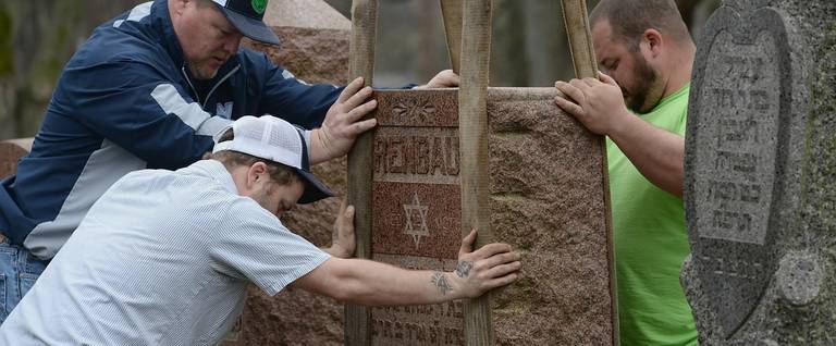 Volunteers from a local monument company help to reset vandalized headstones at Chesed Shel Emeth Cemetery in University City, Missouri, February 22, 2017. 