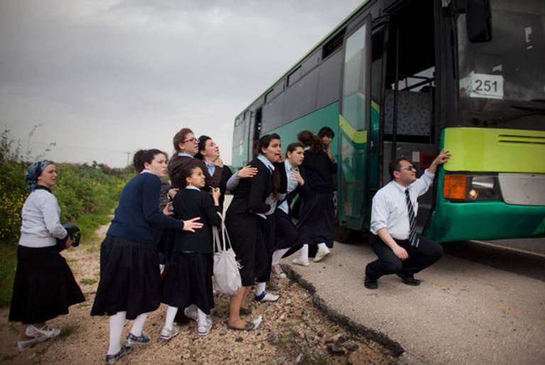 Schoolgirls take cover next to a bus during a rocket attack from the Gaza Strip, on March 12, 2012 in Ashdod, Israel. (Uriel Sinai/Getty Images)