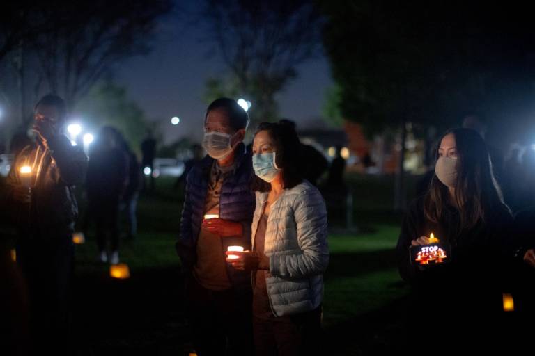 Dr. Mai Khanh Tran, center, stands with her husband, Manh Phi, while mourning at a vigil for those who lost their lives in the Atlanta spa shootings, at Community Center Park in Garden Grove, California, on March 24, 2021. Dr. Tran, a pediatrician, has been active in the fight against anti-Asian hate and has seen it continue to get worse through the years.