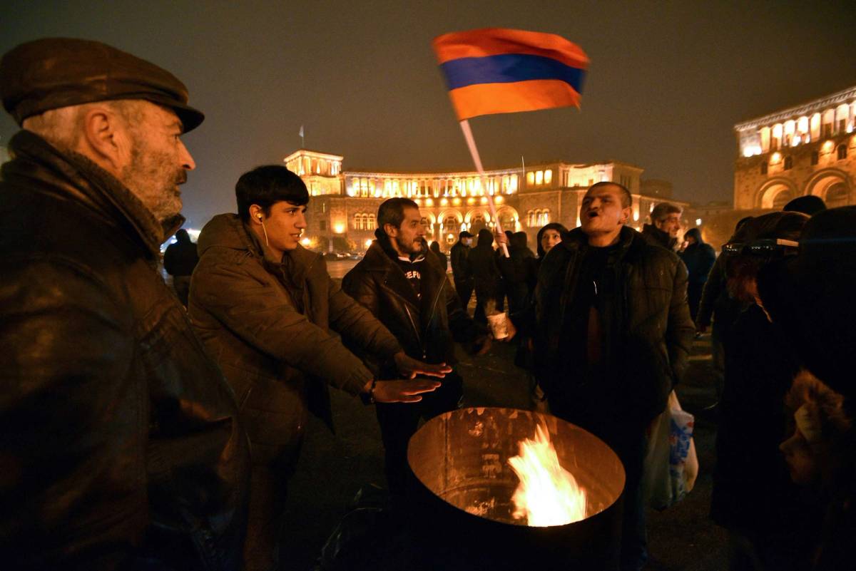 Opposition supporters warm themselves near a bonfire during a rally in Yerevan's Republic Square to demand the resignation of Prime Minister Nikol Pashinyan over a controversial peace deal with Azerbaijan that ended six weeks of war over the disputed region of Nagorno-Karabakh, on Dec. 22, 2020