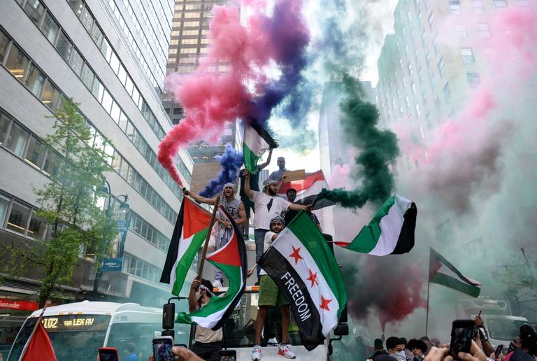 Demonstrators hold Palestinian and Syrian flags in support of Palestine in midtown Manhattan, on May 18, 2021