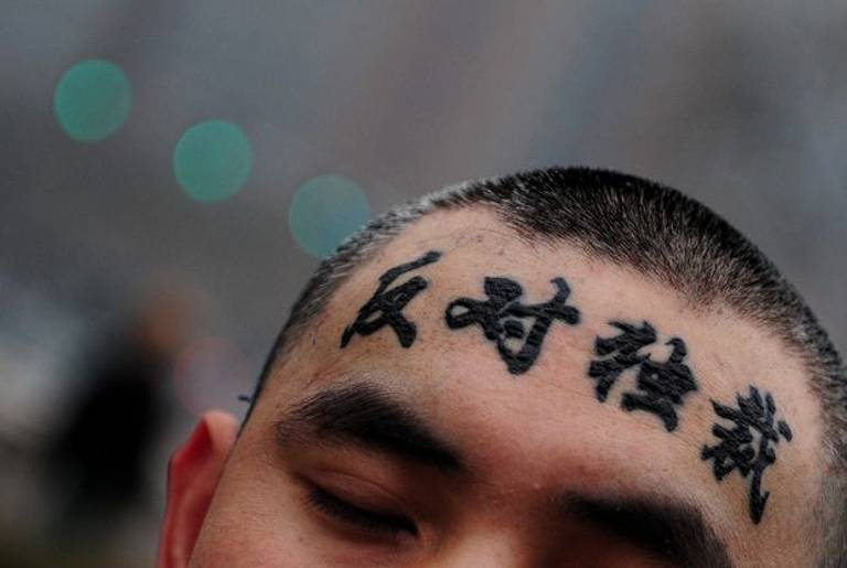 A lone protester displays his forehead after taking off a cap to reveal 'oppose the dictators' in support of China's dissident Liu Xiaobo on Dec. 9, 2009, in Beijing.)