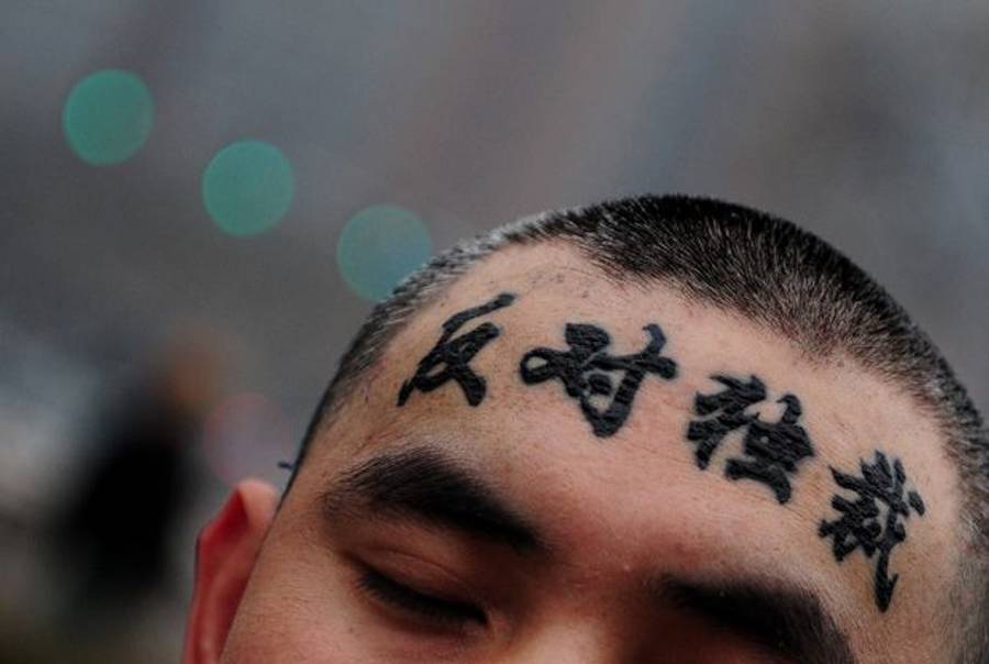 A lone protester displays his forehead after taking off a cap to reveal 'oppose the dictators' in support of China's dissident Liu Xiaobo on Dec. 9, 2009, in Beijing.)