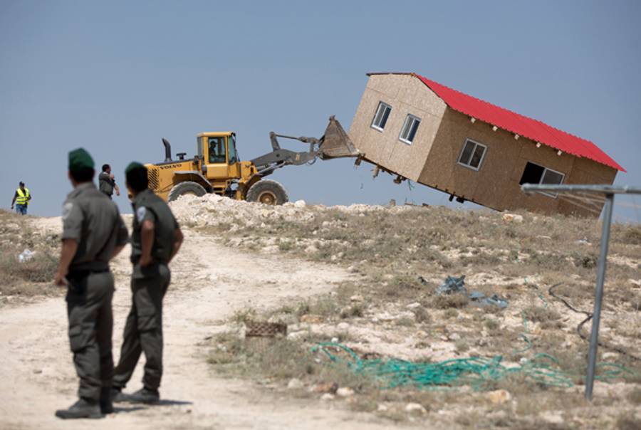An Israeli authority bulldozer demolishes a house in the West Bank settlement of Maale Rehavam on May 14, 2014. (MENAHEM KAHANA/AFP/Getty Images)