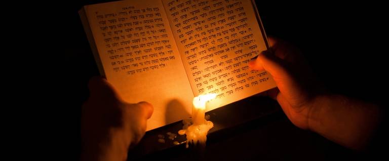 A Jewish man uses a candle to read from the Book of Lamentations during the annual Tisha B'Av fast, commemorating the destruction of the ancient Jerusalem temples, in the Jerusalem neighborhood of Mea Shearim, on July 25, 2015. 
