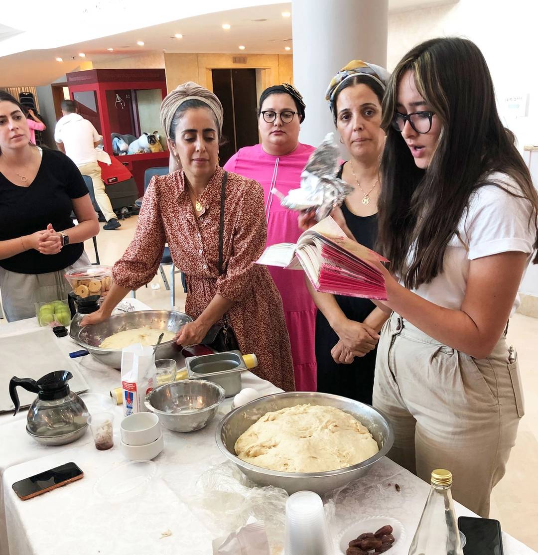 Women make the blessing over the separation of challah in the foyer of the Leonardo Plaza Hotel. ‘The idea is that doing good deeds, especially the mitzvah of separating challah, speeds the departed soul’s entry to heaven,’ the leader explained.
