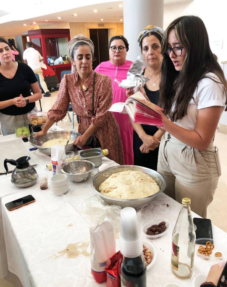 Women make the blessing over the separation of challah in the foyer of the Leonardo Plaza Hotel. ‘The idea is that doing good deeds, especially the mitzvah of separating challah, speeds the departed soul’s entry to heaven,’ the leader explained.