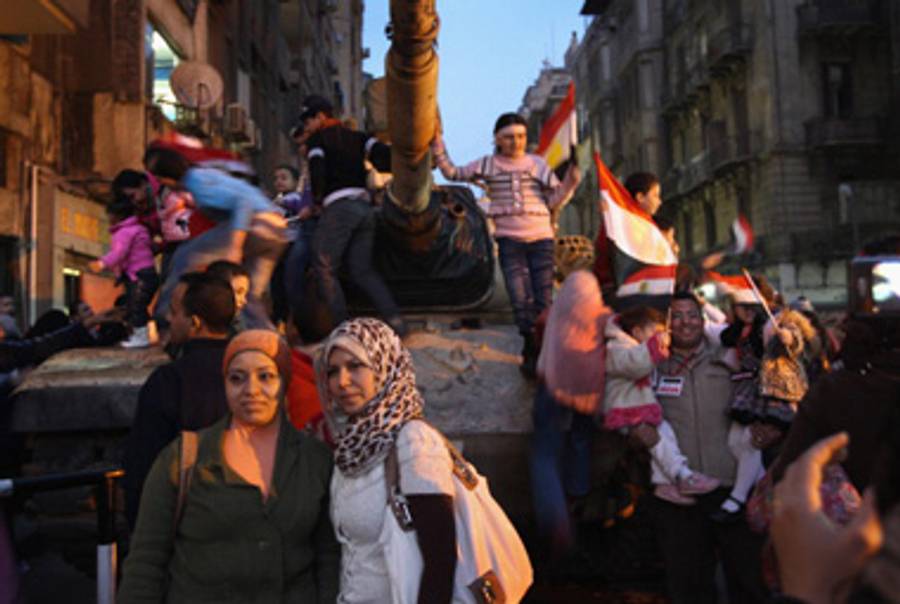 Egyptians pose yesterday on an army tank in Cairo.(John Moore/Getty Images)