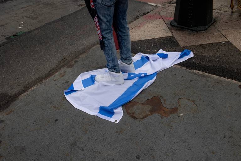 A self-proclaimed Jewish communist steps on an Israeli flag while other Jews proclaim their support for Israel across the street, outside of the Israeli Consulate in midtown Manhattan on Aug. 16, 2021