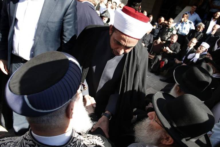 Sheikh Samir Aasi, chief Imam in Akko (C) shakes hand with Sephardi Chief Rabbi of Israel Shlomo Amar (L) during a visit by chief clerics and representatives of different religious communities to the synagogue where two Palestinians killed five Israelis in Jerusalem the previous day, on November 19, 2014.(THOMAS COEX/AFP/Getty Images)