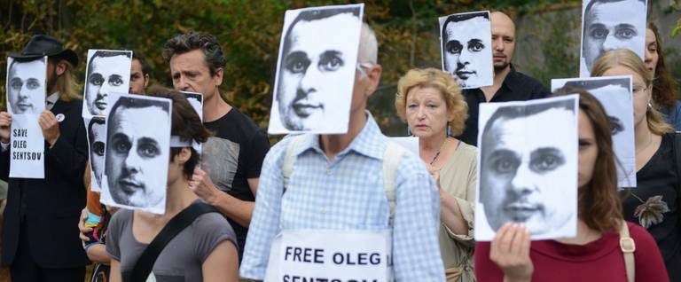 People wearing masks depicting Ukrainian film director Oleg Sentsov take part in a protest on Aug. 28, 2018, in front of the Russian embassy in Prague.