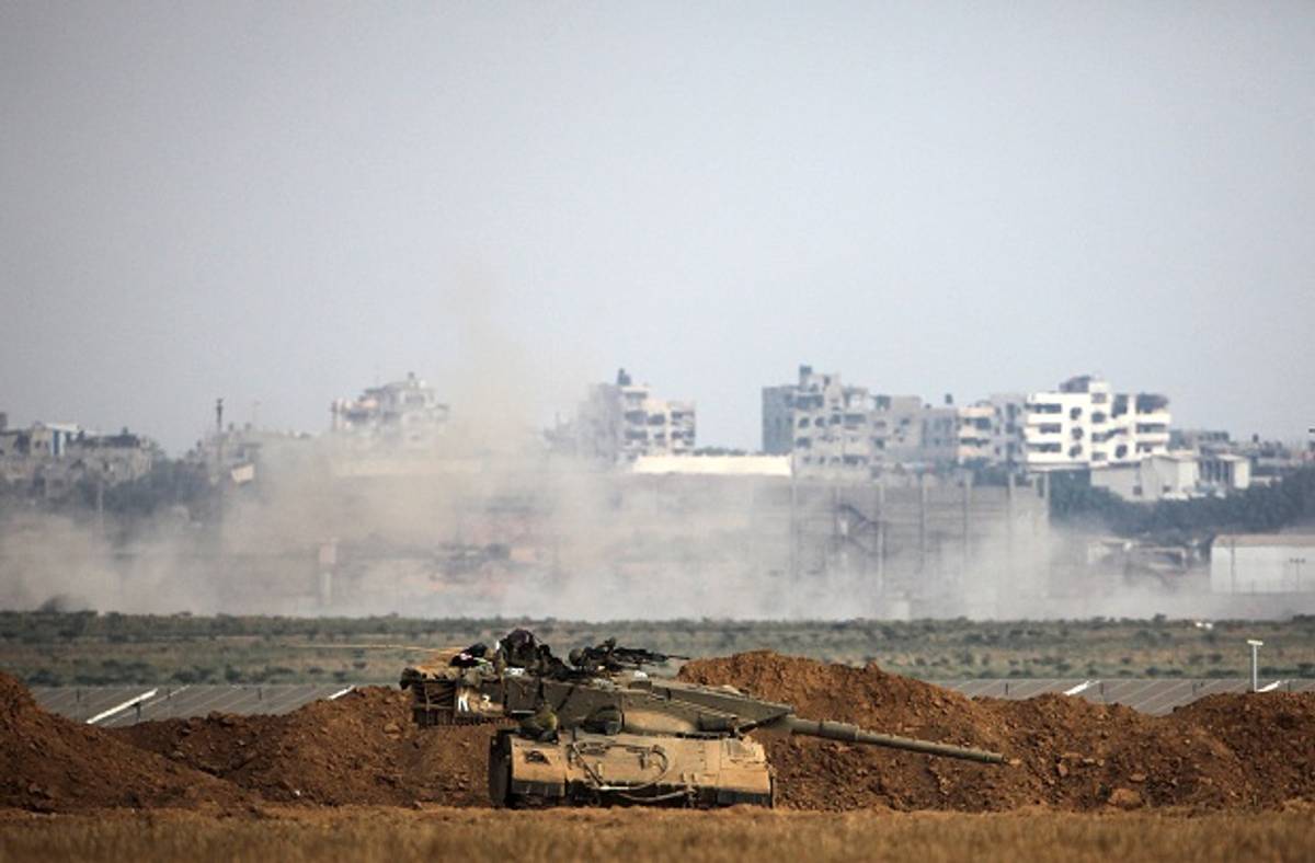 A picture taken from the Israeli side shows an Israeli army Merkava tank positionned along the border in front of buildings in the Gaza Strip on July 28, 2014. (Getty Images)