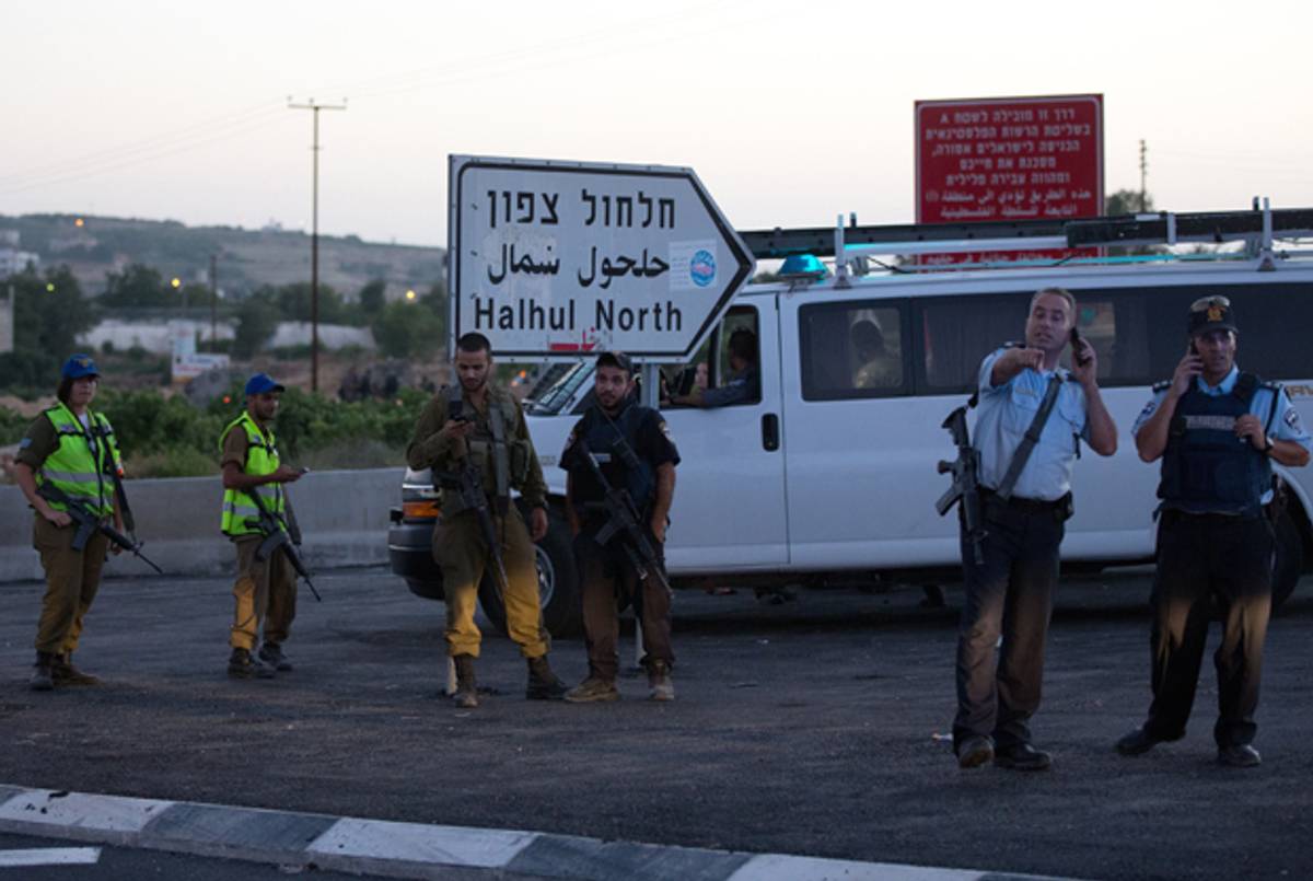 Israeli security forces speak on the phone as they stand guard on June 30, 2014 in the village of Halhul, near the West Bank town of Hebron, where the bodies of the three missing Israeli teenagers were found. (MENAHEM KAHANA/AFP/Getty Images)