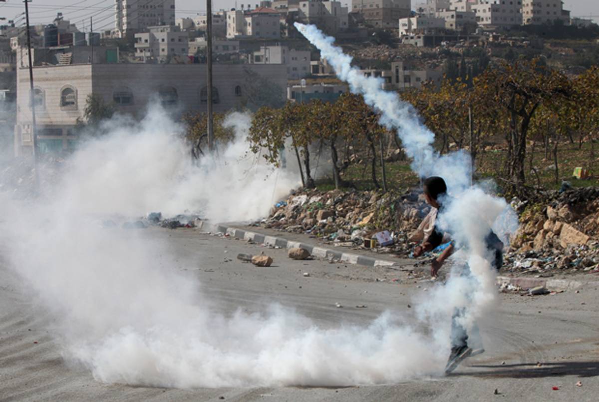 Palestinian throws back a tear gas grenade at Israeli soldiers during clashes near West Bank city of Hebron on November 11, 2014. (HAZEM BADER/AFP/Getty Images)