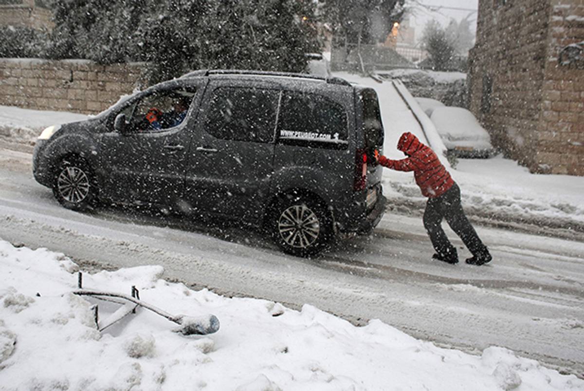 A man pushes a car up a hill in Jerusalem on Jan. 7, 2015, as a snow storm hit the region. (AHMAD GHARABLI/AFP/Getty Images)