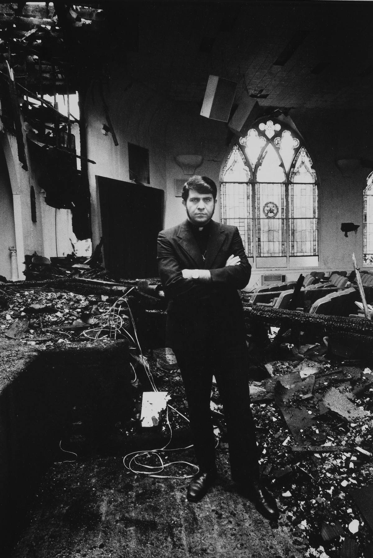 Perry stands in his burned-down church, Los Angeles, 1973