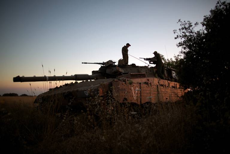 Israeli soldiers are seen on their Merkava tank positioned near the Quneitra checkpoint on the border with Syria in the Golan Heights on June 22, 2014, after an Israeli teen was killed in an attack from Syria. (MENAHEM KAHANA/AFP/Getty Images)