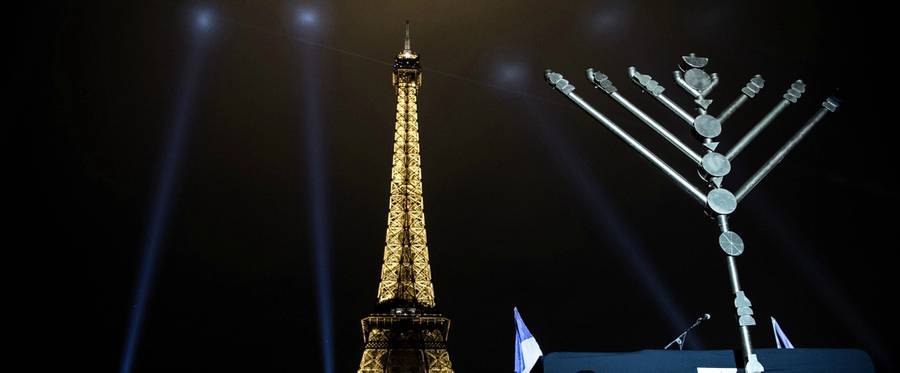 A member of the Jewish community stands near a Menorah (Hanukkah), a nine-branched candelabrum, before the lighting of two branches in front of the Eiffel tower in Paris on December 25, 2016.