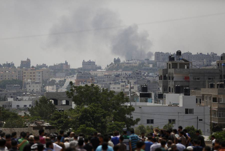 Smoke from an Israeli offensive is seen as people gather at a cemetery during the funeral for members of the al-Kelani family in Beit Lahia in the northern Gaza Strip, on July 22, 2014. (MOHAMMED ABED/AFP/Getty Images)