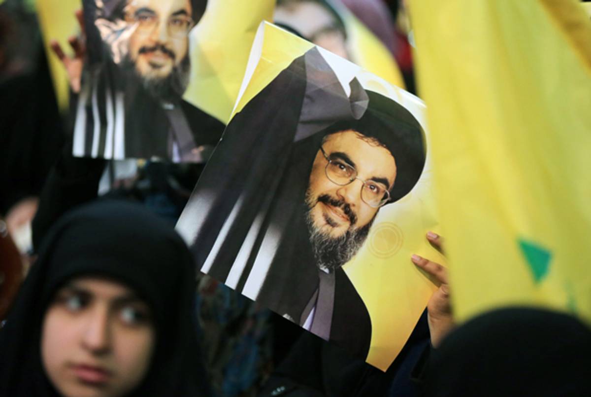 A Shiite supporter holds a poster showing Hassan Nasrallah, the head of Lebanon's militant Shiite Muslim movement Hezbollah, as he addresses supporters through a giant screen during a meeting in Beirut's southern suburb of Mujammaa Sayyed al-Shuhada on January 30, 2014. (JOSEPH EID/AFP/Getty Images)
