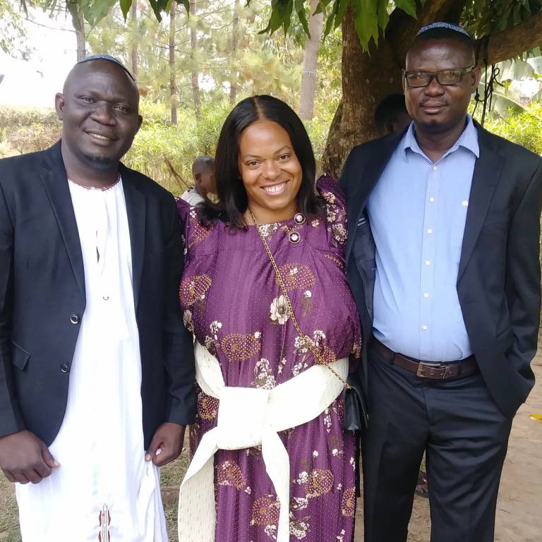 The author, at center, with her husband Israel Ziraba, right, and brother-in-law Allan Ziraba. The author wears a traditional Ugandan women’s dress called a gomesi, and Allan wears a kanzu robe, which is traditional Ugandan formal wear.