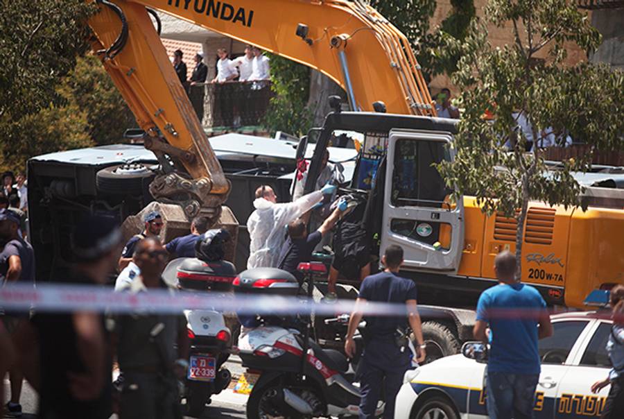 Israeli policemen moves the body of a Palestinian man who was shot by Israeli police officers after he rammed an excavator into a bus on August 04, 2014 in Jerusalem, Israel. (Lior Mizrahi/Getty Images)