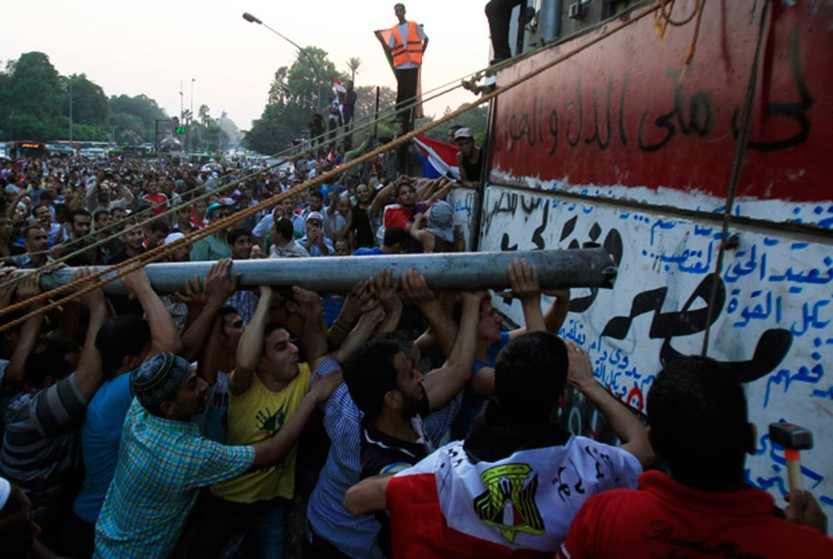 Protesters knock down a concrete wall in front of the Israeli Embassy in Cairo on Friday.(Amr Dalsh/Reuters)