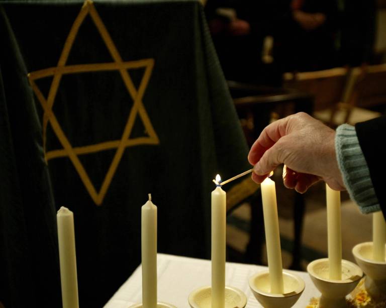 A woman lights a candle during a ceremony in Palma de Mallorca's synagogue, Jan. 26, 2006, on the eve of Holocaust Memorial Day