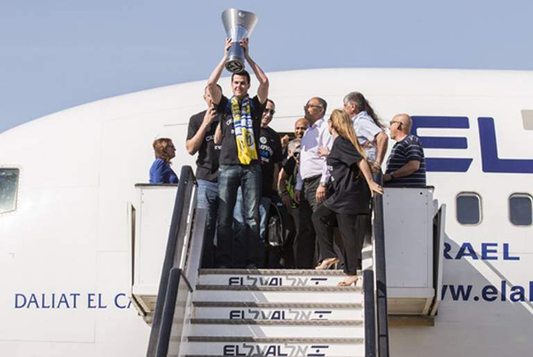 Maccabi Tel Aviv forward Guy Pnini holds the trophy as the Israeli basketball team arrives at Ben Gurion airport, on May 19, 2014 after winning the Euroleague 2014 Final Four basketball match against Real Madrid. (Maccabi Tel Aviv Wins Euroleague Basketball)
