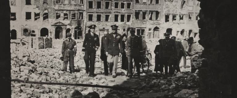Gen. Dwight D. Eisenhower with other military and civilian officials gathered in the rubble of Warsaw, 1946