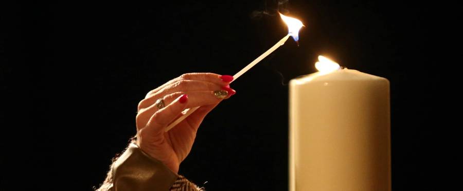 A woman lights a candle during an event to commemorate Holocaust Memorial Day at the Imperial War Museum on January 27, 2016 in London, England. 