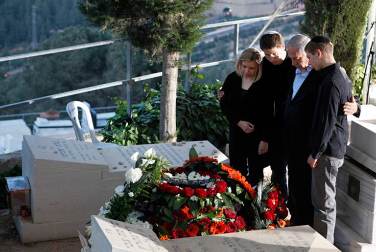 Israeli Prime Minister Benjamin Netanyahu, his wife Sara, and their sons stand at the grave of the premier's father following his funeral Monday in Jerusalem. (Gali Tibbon/AFP/Getty Images)