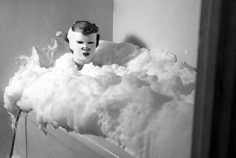 A masked woman in a foaming milk bath at Helena Rubinstein's New York salon, 1937. 