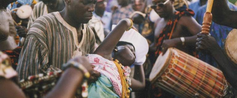 A young woman falls into trance during a procession in southern Ghana. The procession is part of a week-long Akan religious festival. The man supporting her is Kwadjo Opare, a prince and member of the royal drumming ensemble.