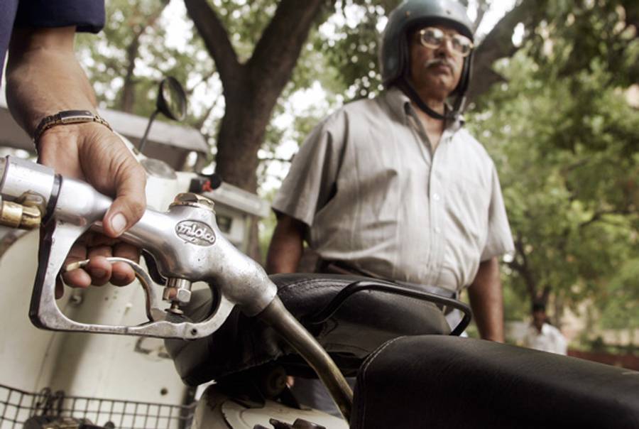 An Indian commuter looks on as a petrol station attendant fills his scooter tank, in New Delhi.(Christophe Archambault/AFP/Getty Images)